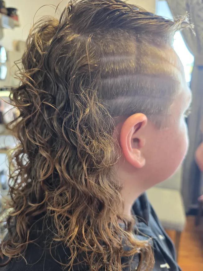 A young boy with curly hair and a shaved head.