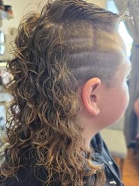 A young boy with curly hair and a shaved head.
