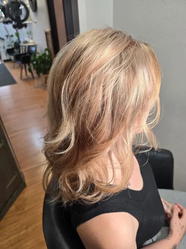 A woman with blonde hair is sitting in a chair in a salon.
