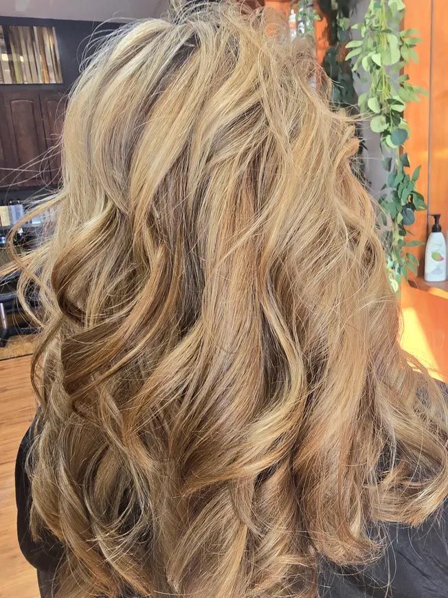 A woman with long blonde hair is sitting in a chair in a salon.