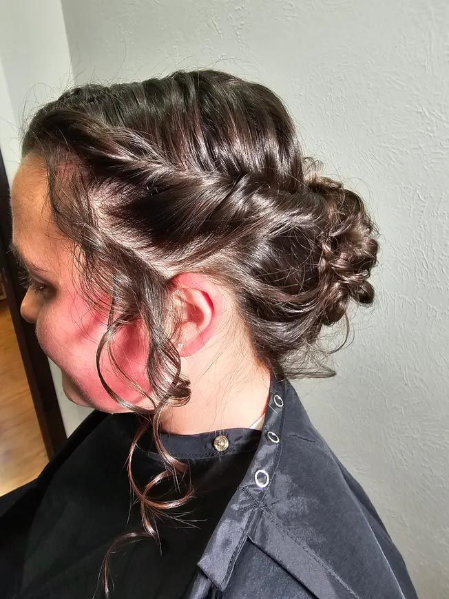 A woman is sitting in a chair with her hair in a bun.