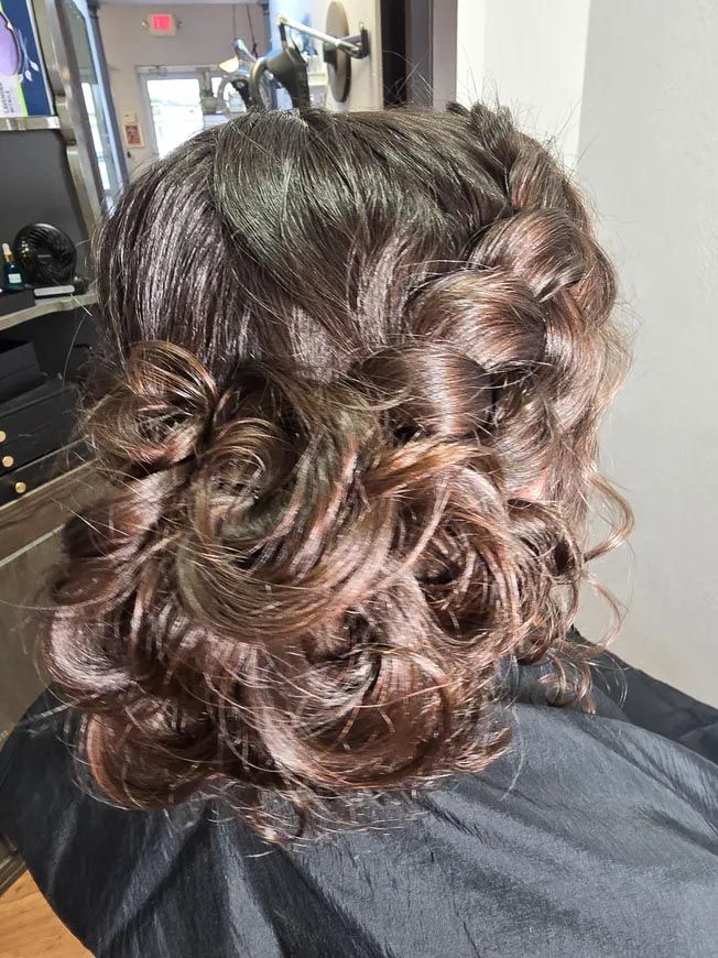 A woman is sitting in a chair with her hair in a bun.