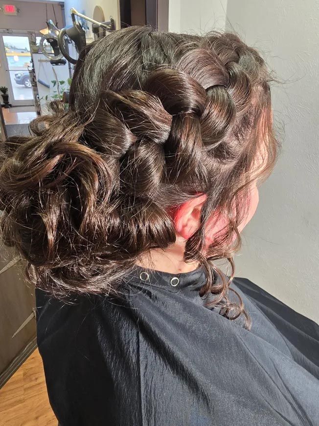 A woman is sitting in a chair with her hair in a braided bun.
