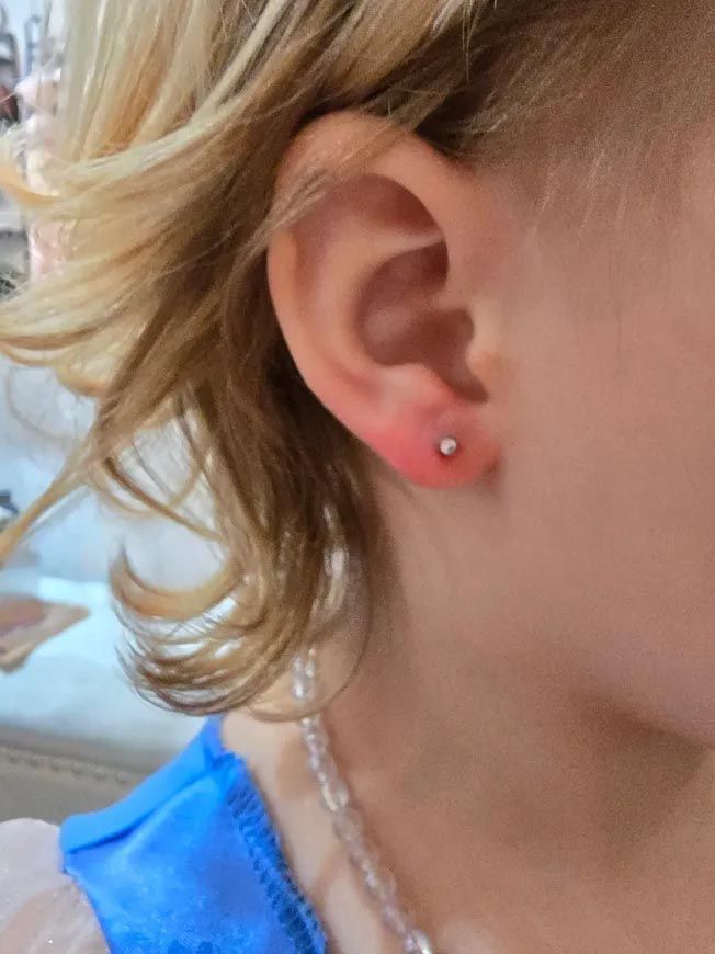 A close up of a child 's ear with earrings