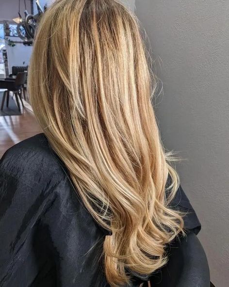 A woman with long blonde hair is sitting in a chair in a salon.
