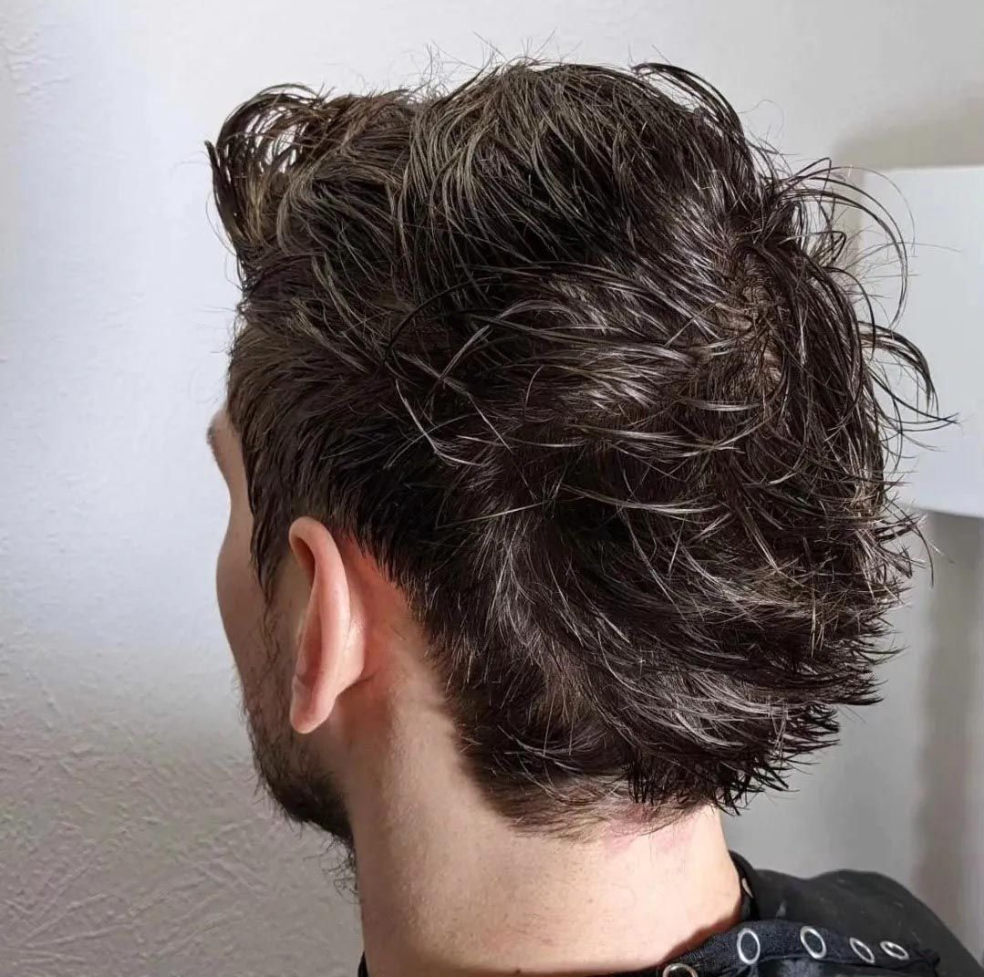The back of a man 's head with a beard and wet hair.