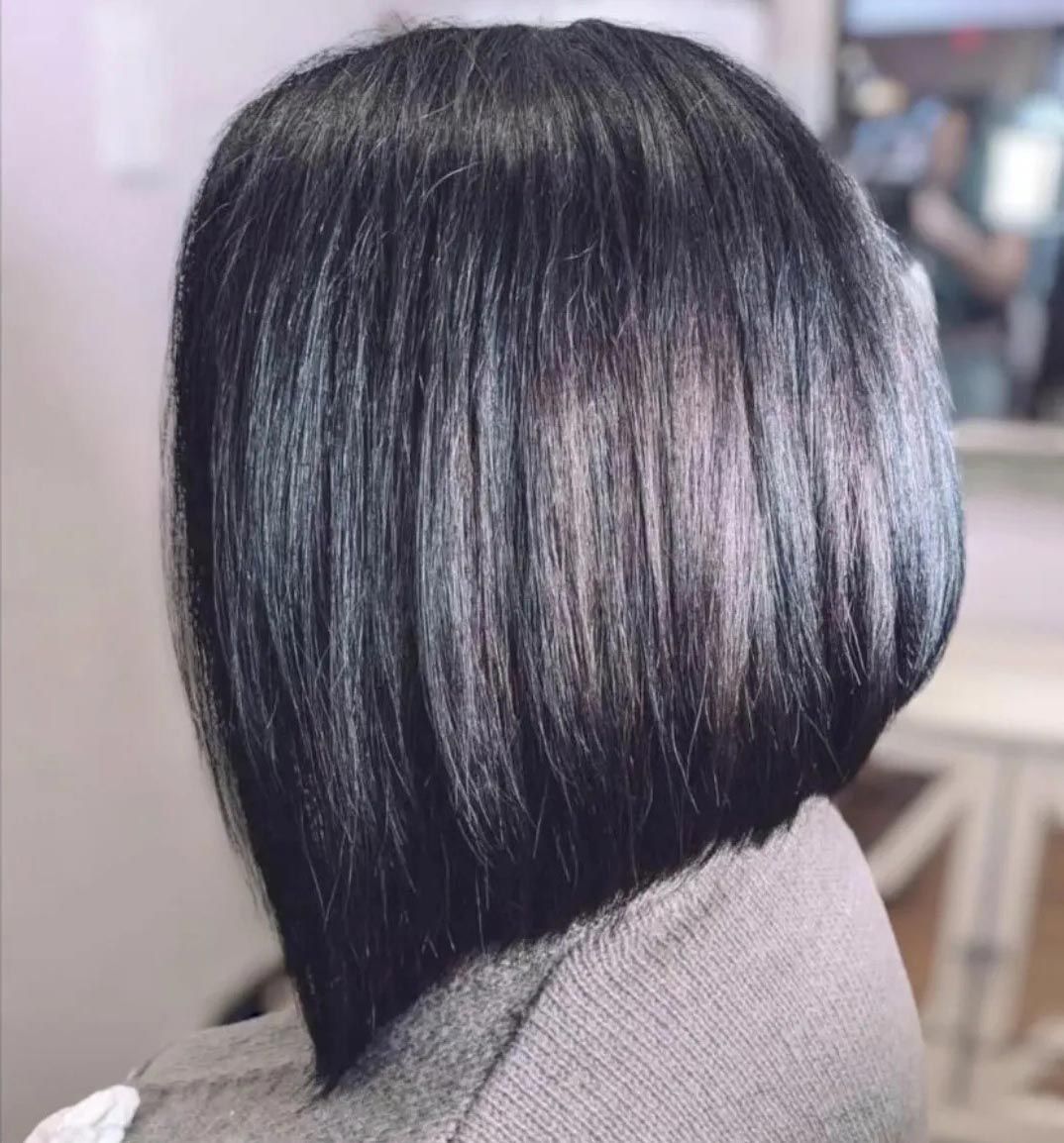 A woman is sitting in a chair with her hair in a bob.