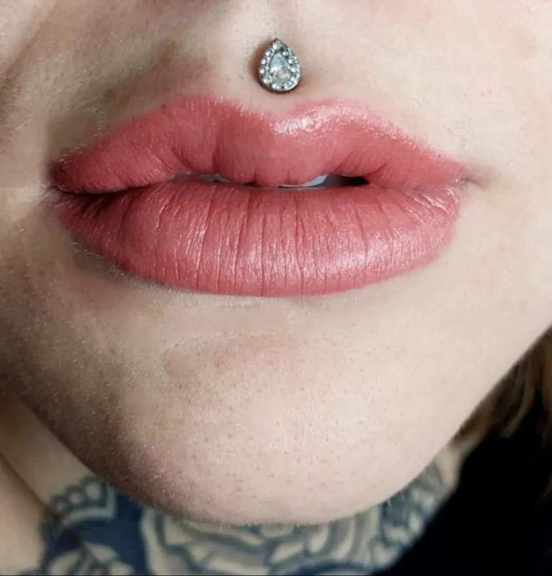 A close up of a woman 's lips with a nose ring.