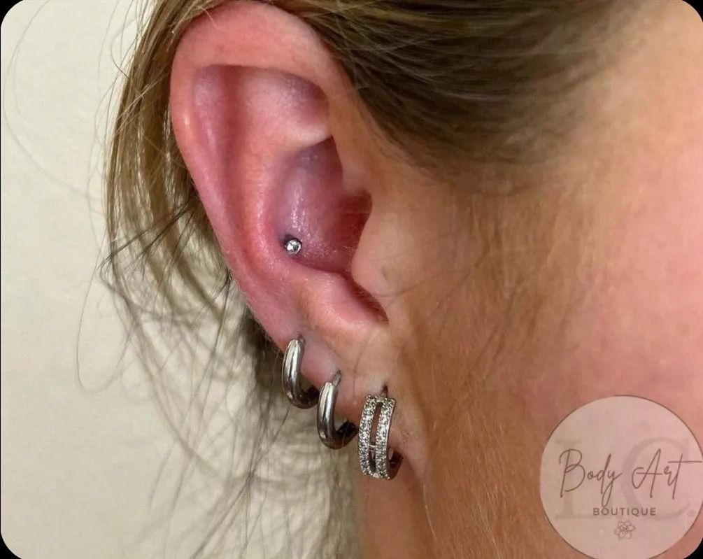 A close up of a woman 's ear with multiple piercings.