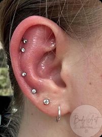 A close up of a woman 's ear with multiple piercings.