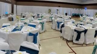 Round banquet tables set with white and blue chair covers in a decorated event hall