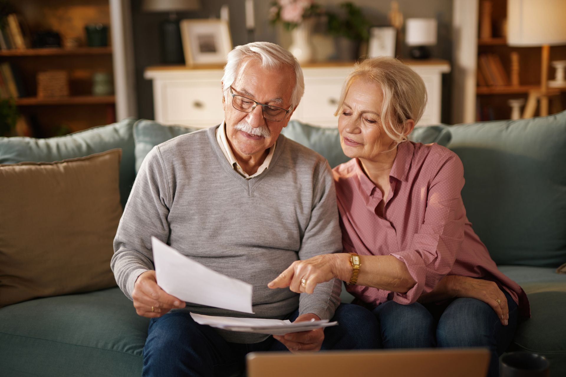 Two people reviewing papers on a couch in a cozy living room