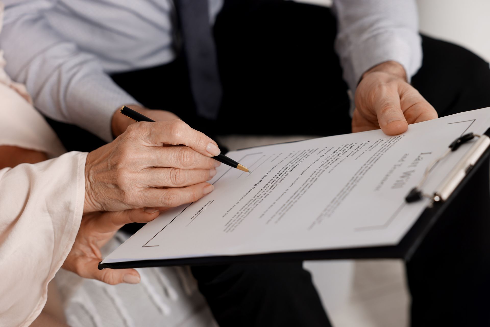 Real estate meeting with a house model, documents, calculator, and hands discussing a contract on a table Real estate meeting with a house model, documents, calculator, and hands discussing a contract on a table