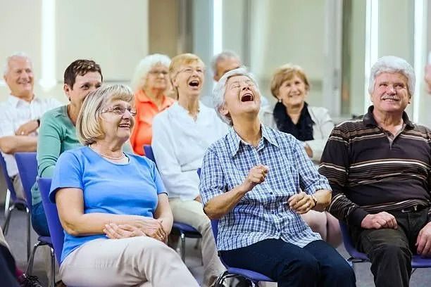 Smiling group seated indoors, laughing during a social gathering or class