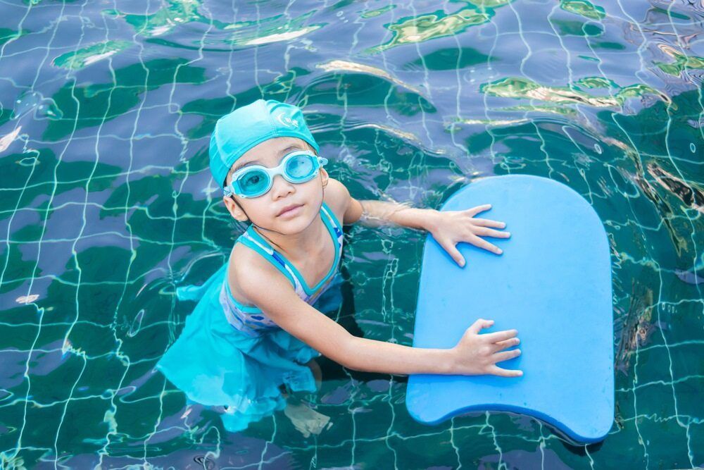 A Little Girl is Holding a Foam Board in a Swimming Pool — North Wyong Aqua Centre In Wyong, NSW