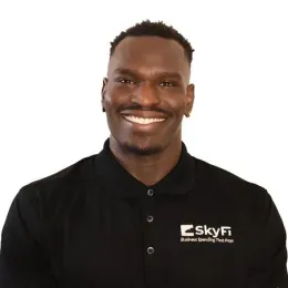 A man wearing a black polo shirt is smiling for the camera.