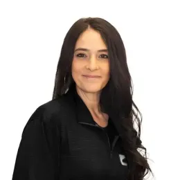 A woman with long hair is wearing a black jacket and smiling.