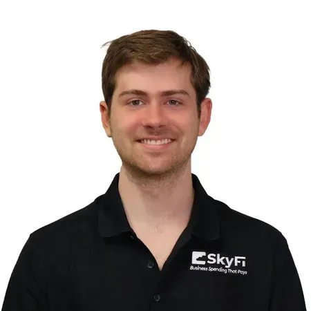 A man wearing a black shirt with the word skyfi on it is smiling.