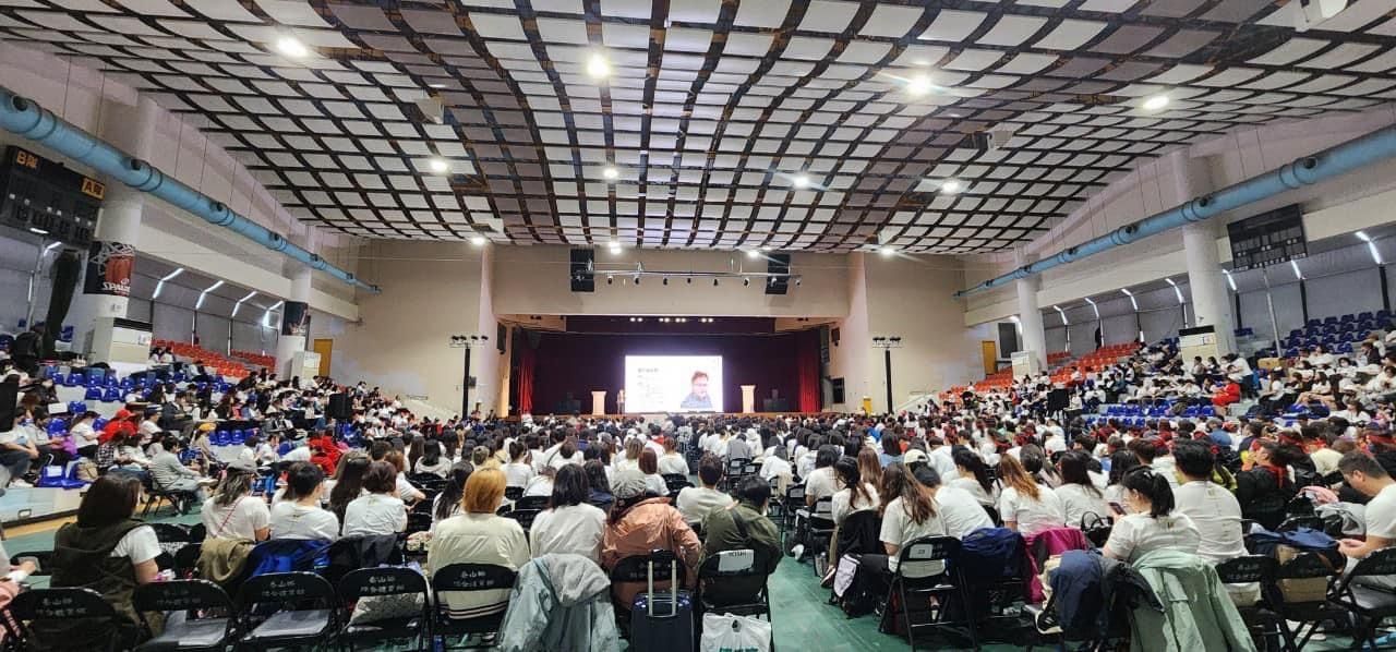 A large group of people are sitting in a large auditorium.