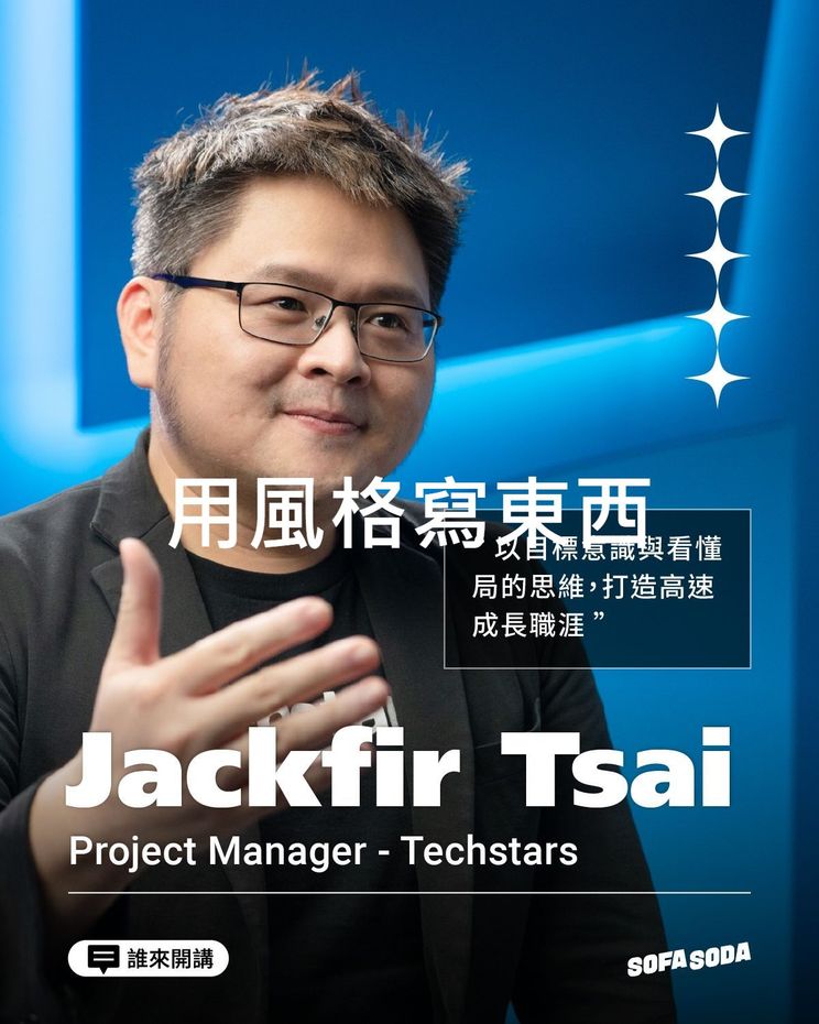 A man wearing glasses and a black jacket is giving a thumbs up