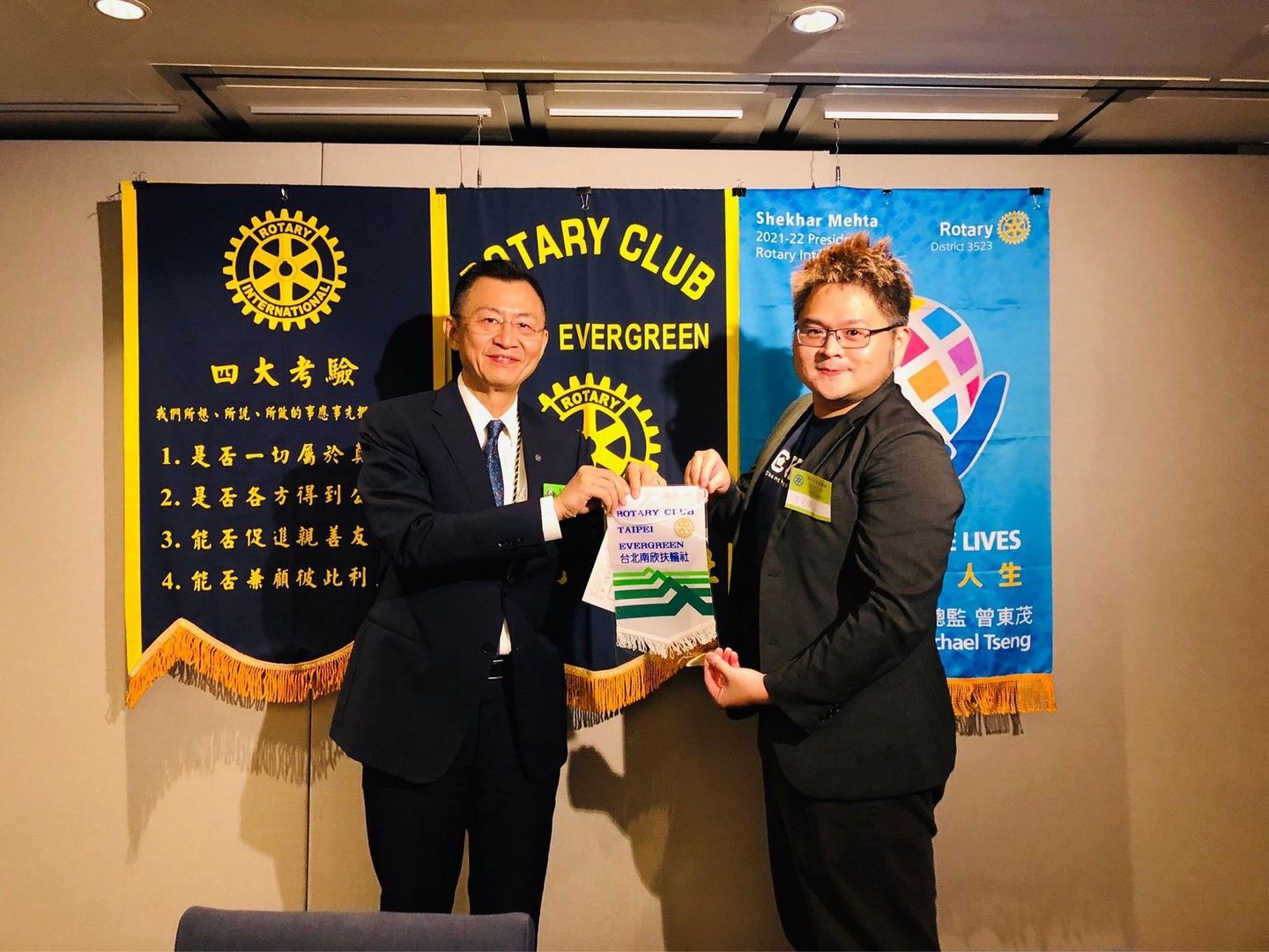 Two men are standing in front of a banner that says rotary club evergreen