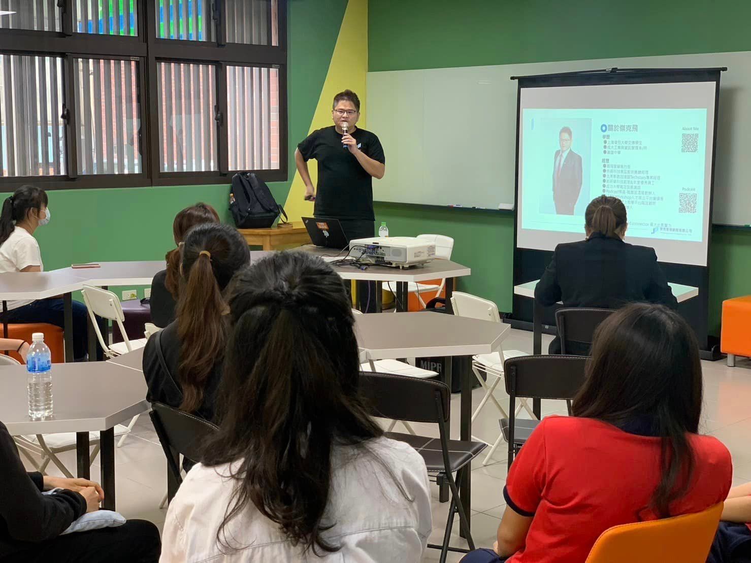 A man is giving a presentation to a group of people in a classroom.