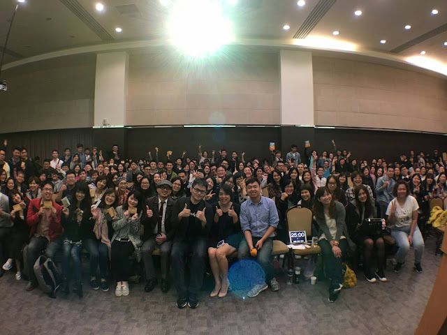 A large group of people are posing for a picture in a large room.