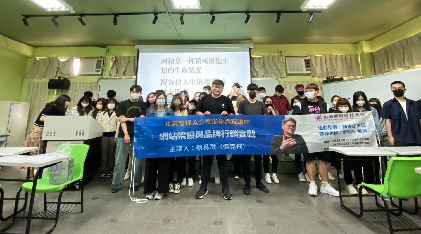 A group of people are standing in a classroom holding a blue banner.