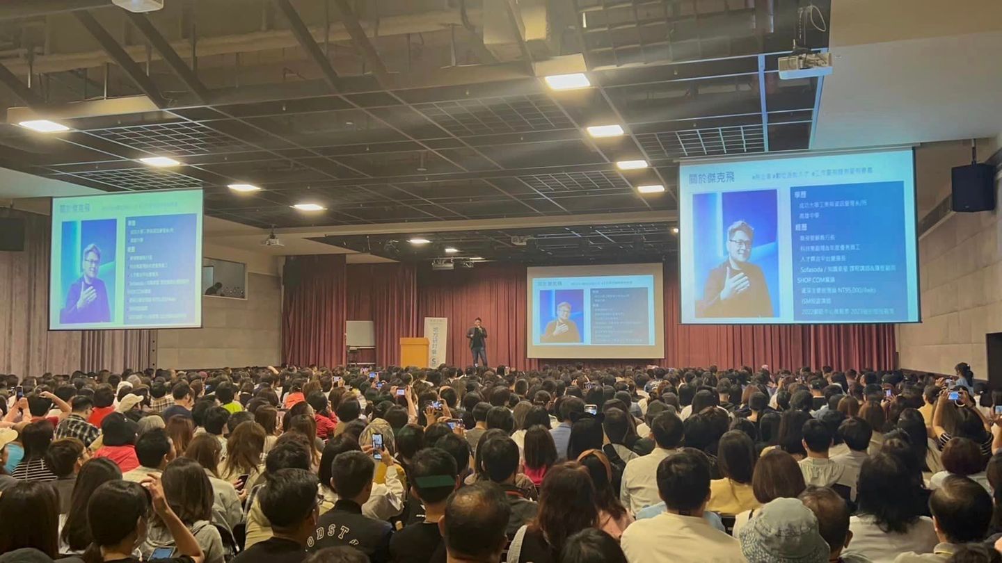 A large group of people are sitting in a large auditorium watching a presentation.