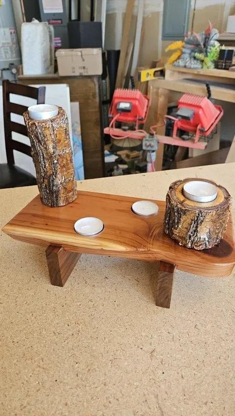 Wooden serving tray with two candle holders and three white tealights on a workbench.