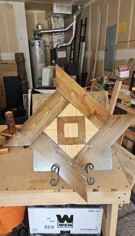 Wooden geometric frame with a square center on a workbench in a workshop, surrounded by tools and materials