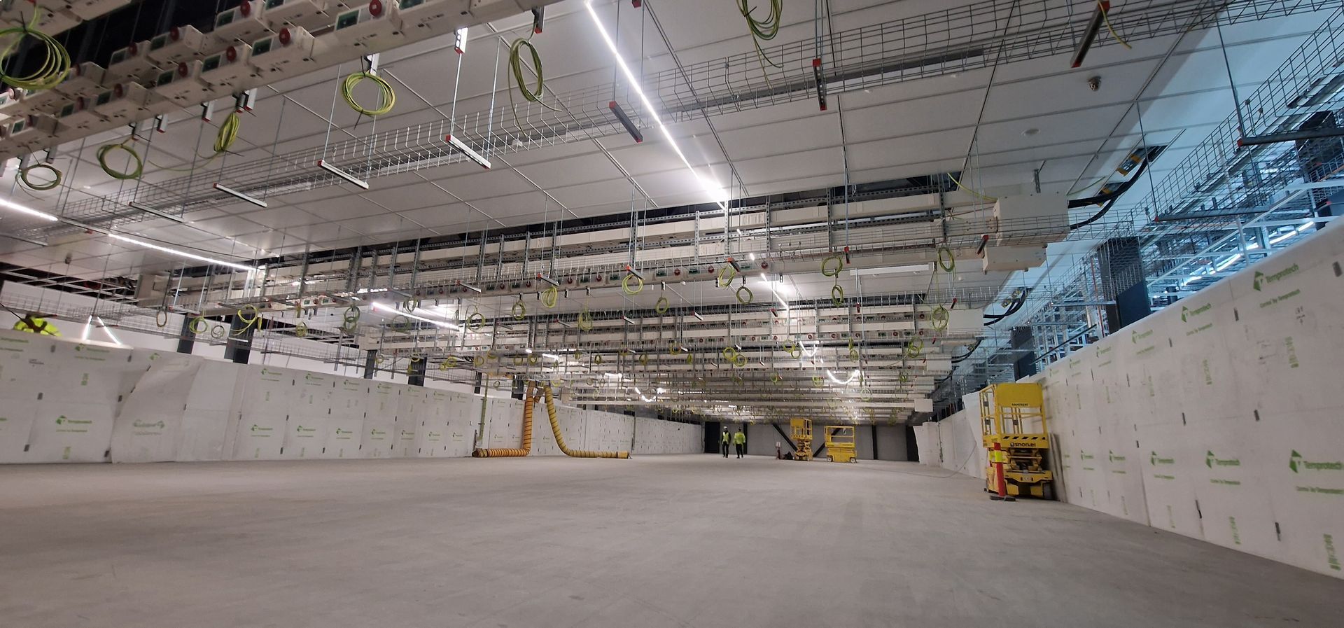 Et stort tomt rom med mange ledninger hengende fra taket.