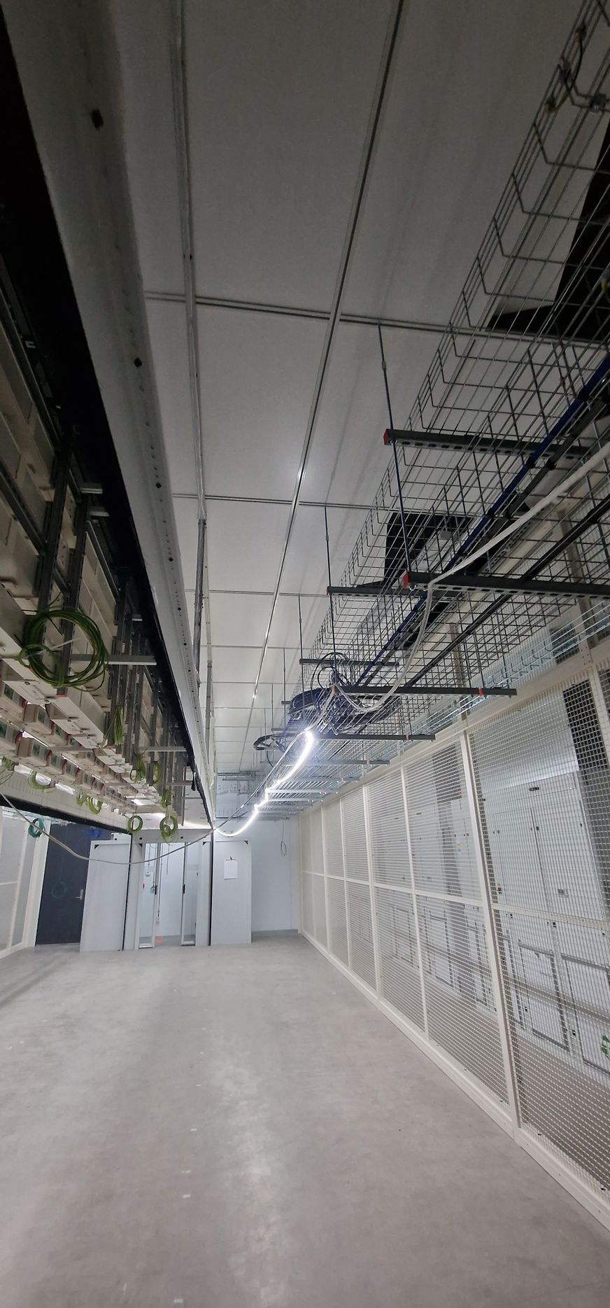 En lang tom gang med mange rør hengende i taket.