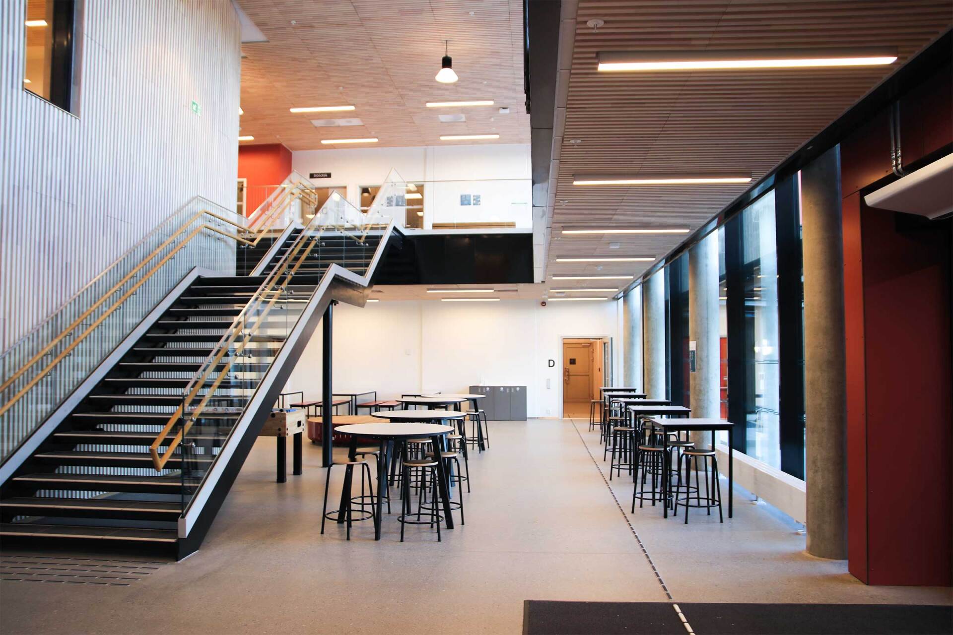 En stor gang med trapper og bord i en bygning.