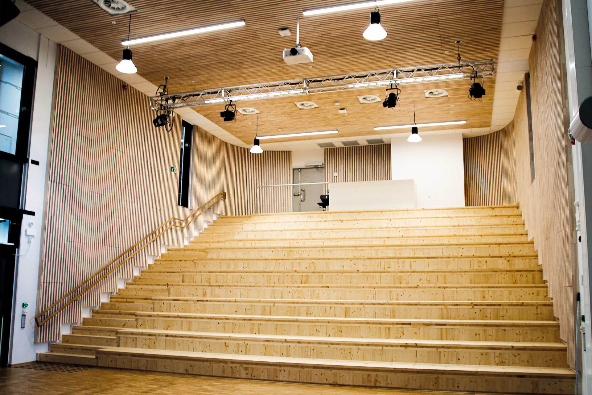Et stort auditorium med tretrapper og en projektor i taket.