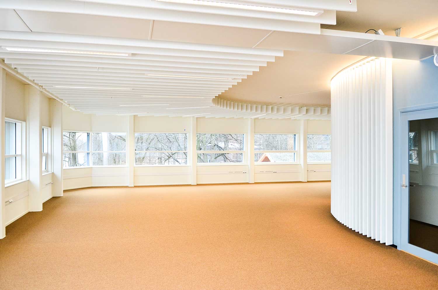 Et stort tomt rom med mange vinduer og en buet vegg.