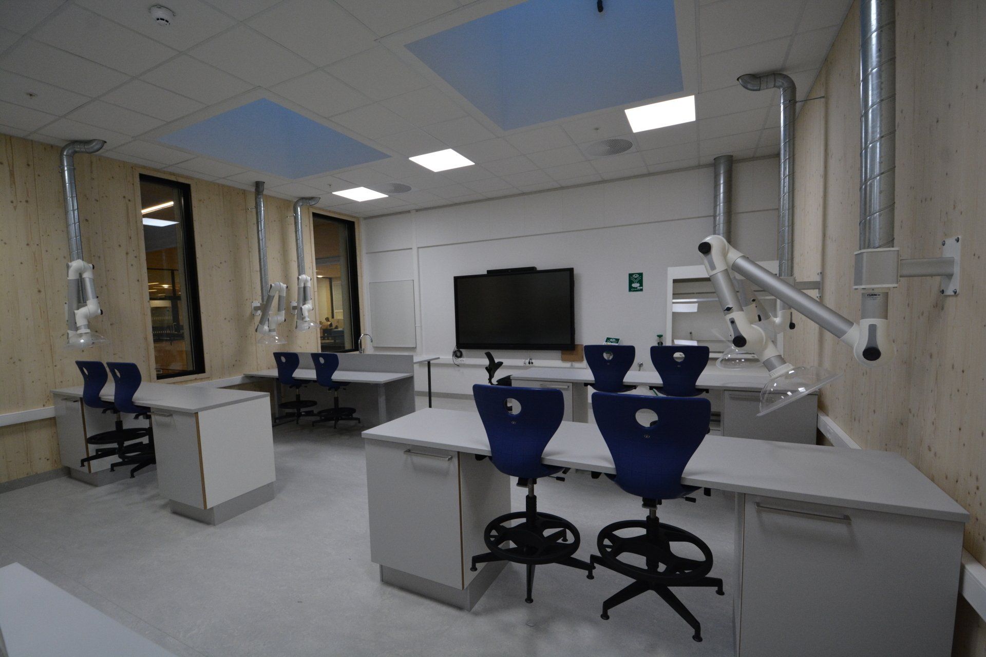Et klasserom med bord, stoler, monitor og mikroskop.