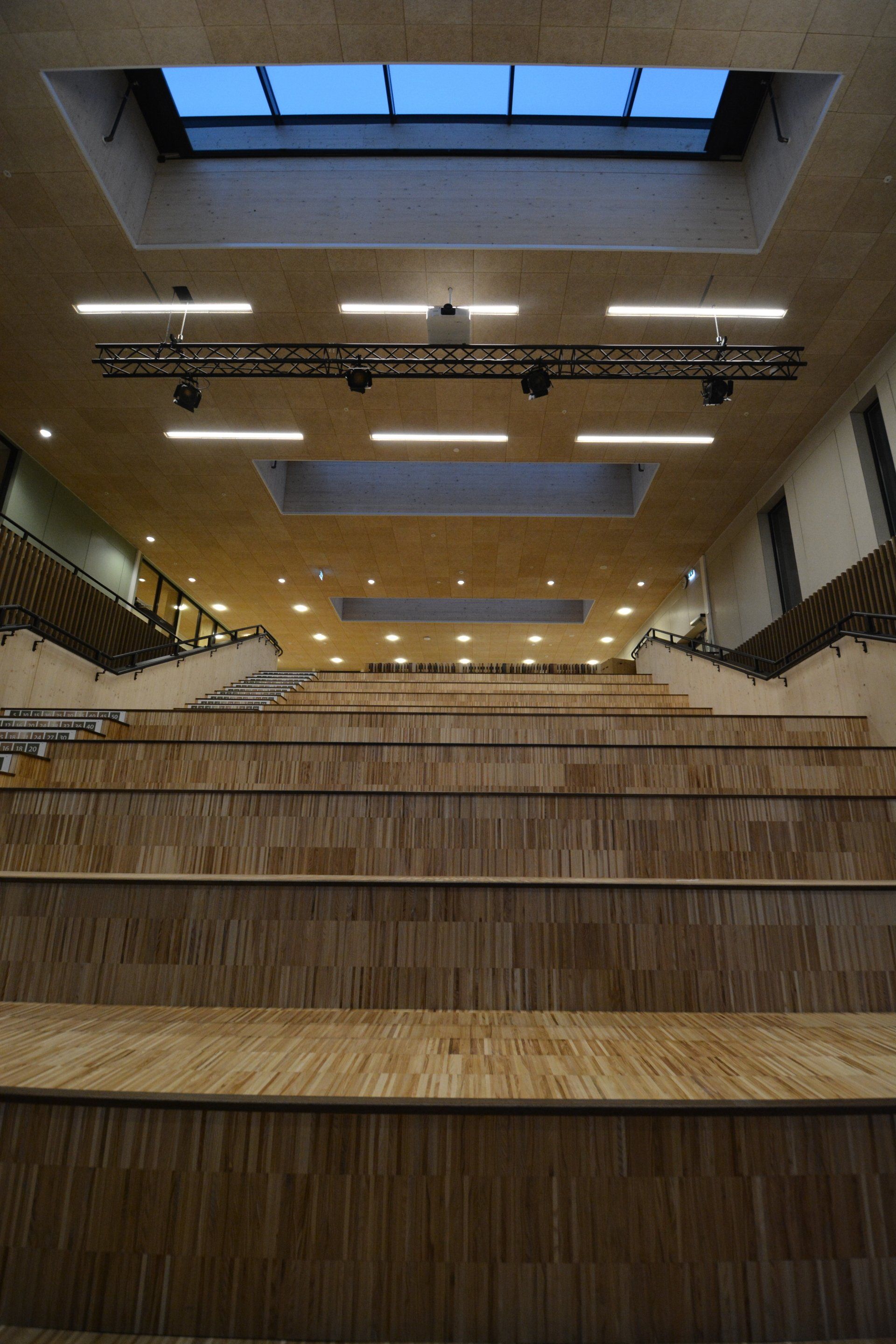 Et stort auditorium med tretrapper og takvindu i taket.