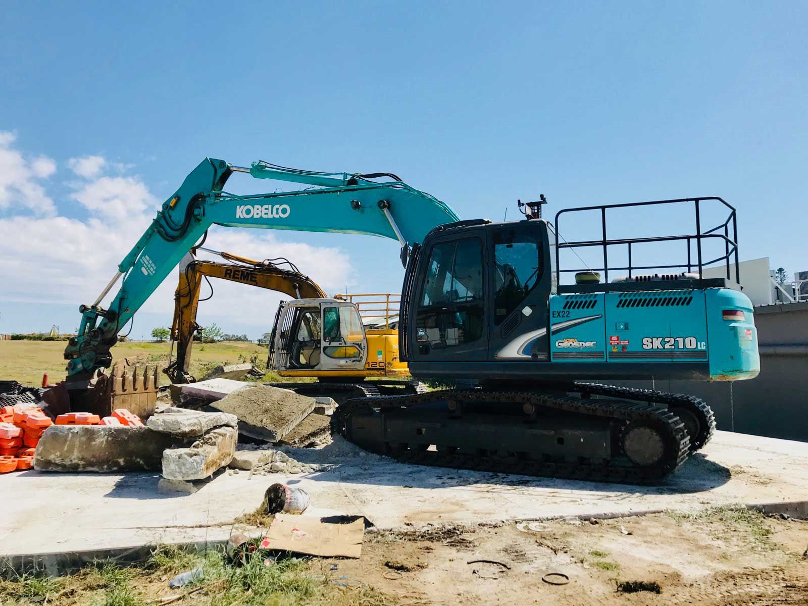 A blue and yellow excavator is parked on a construction site.