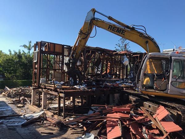 A large yellow excavator is demolishing a building.