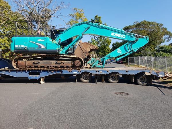 A kobelco excavator is sitting on top of a trailer.