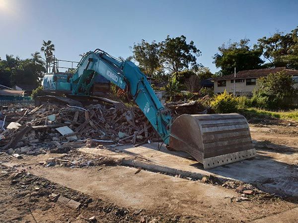 A large excavator is sitting on top of a pile of rubble.