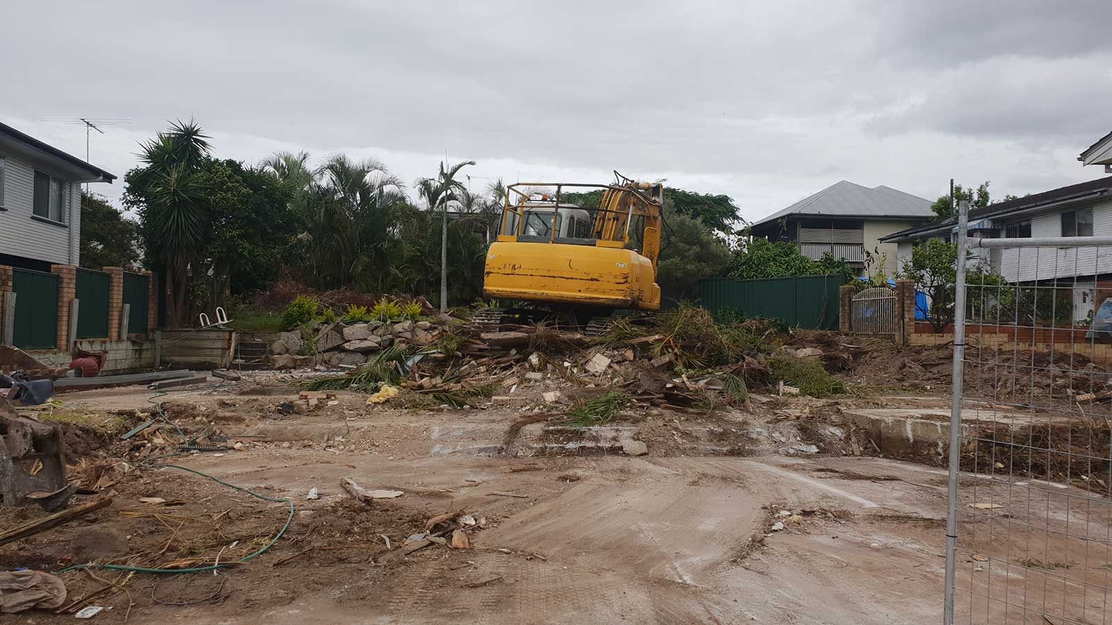 A yellow excavator is driving down a dirt road in a construction site.