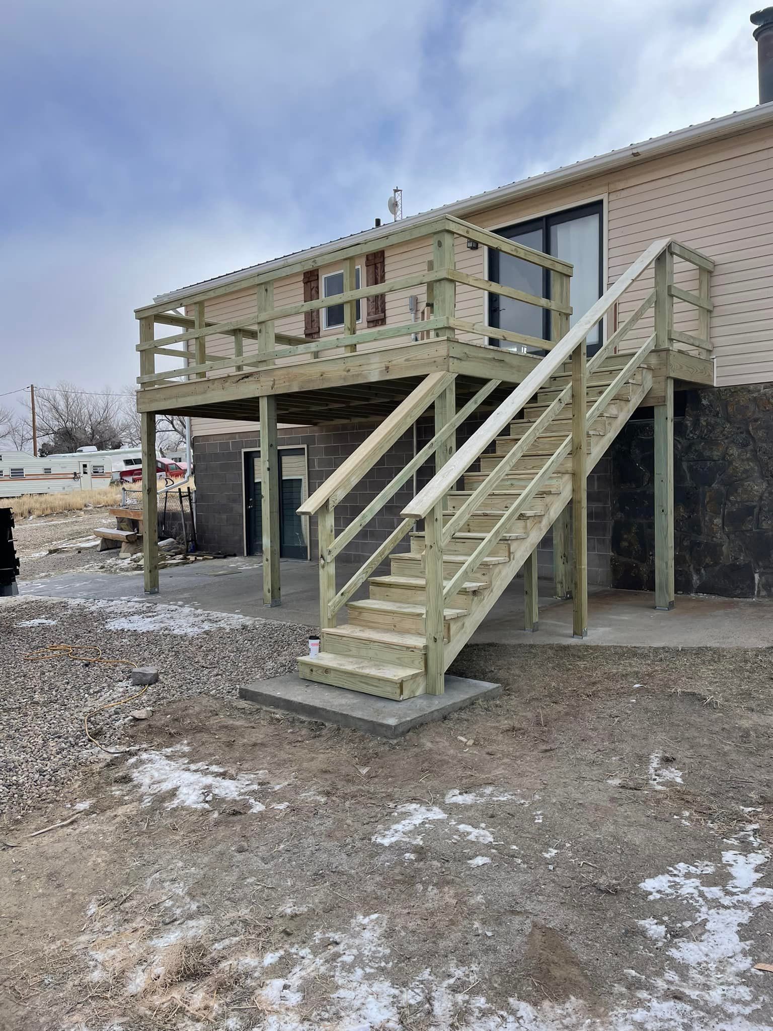 Wooden deck with stairs attached to a building, constructed on cinder blocks.