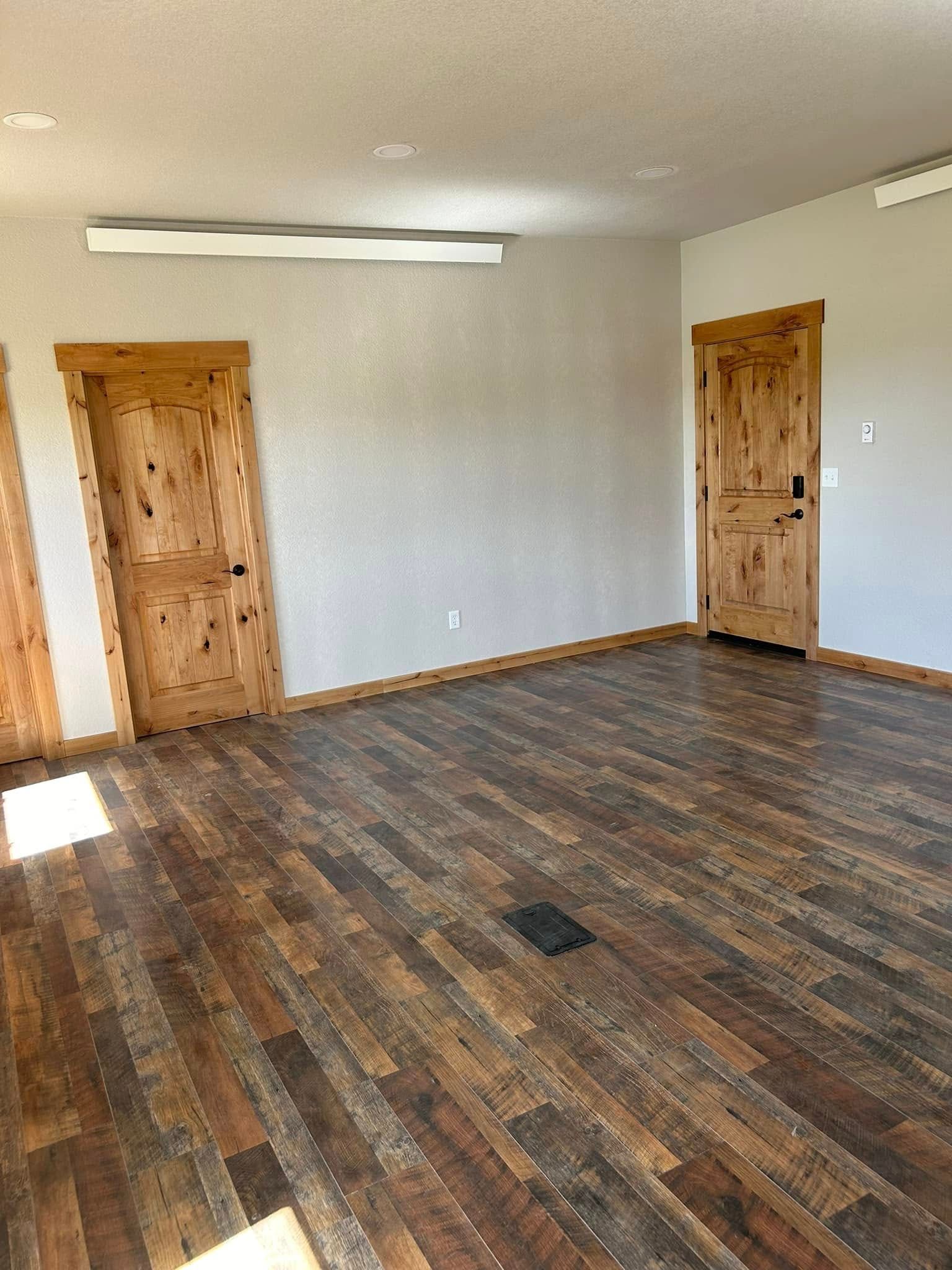 Empty room with wood floors and three wooden doors. White walls and ceiling.