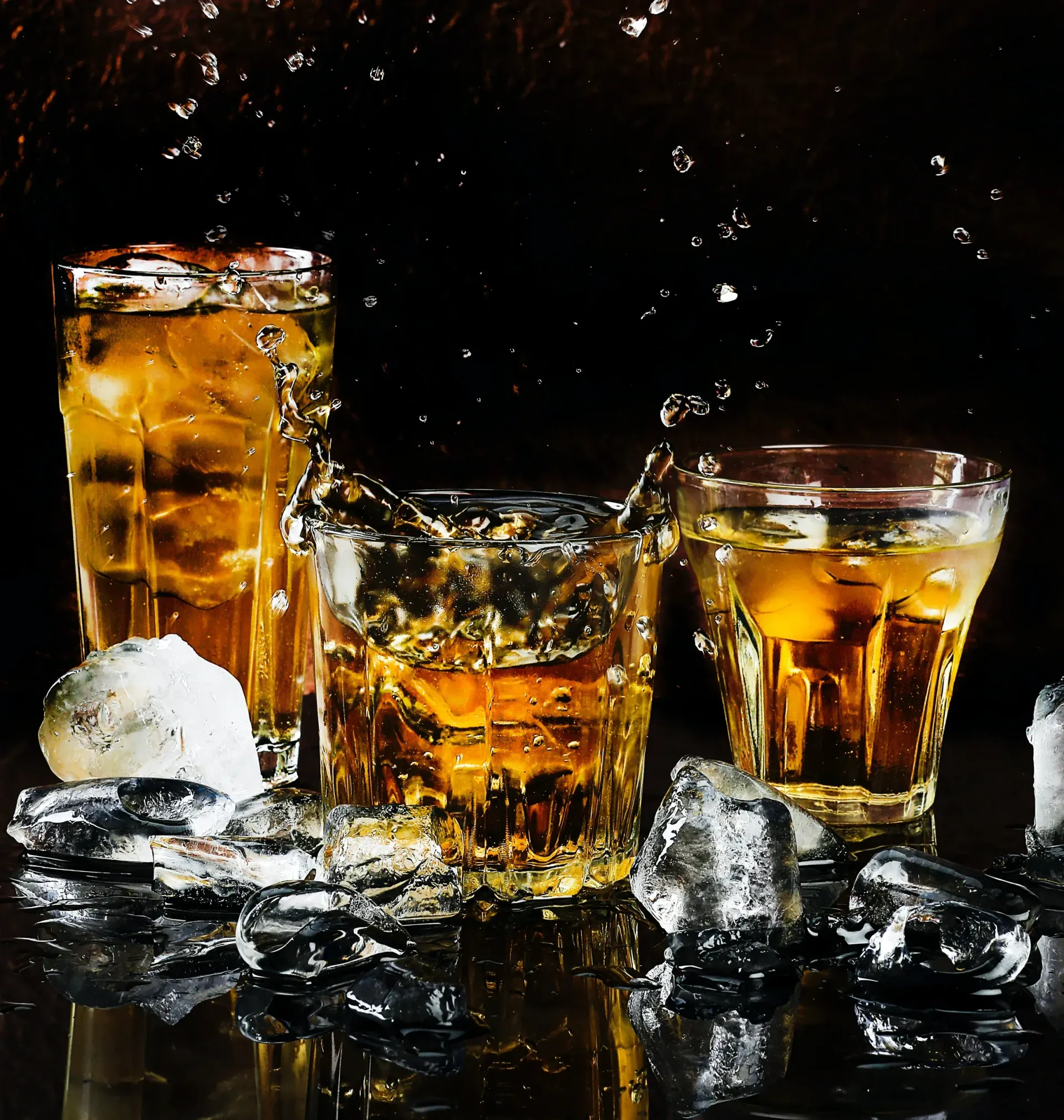 Three glasses of whiskey with ice on a table