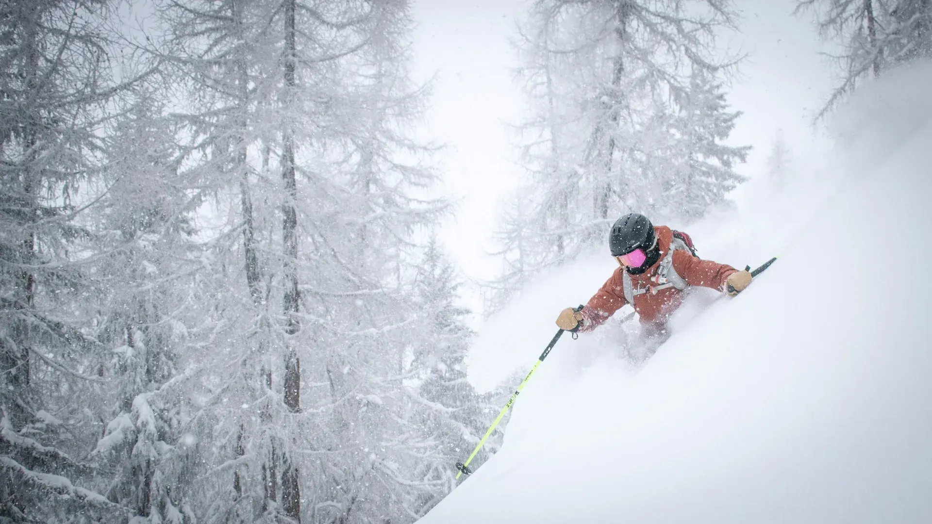 A person is skiing down a snow covered slope in the woods.