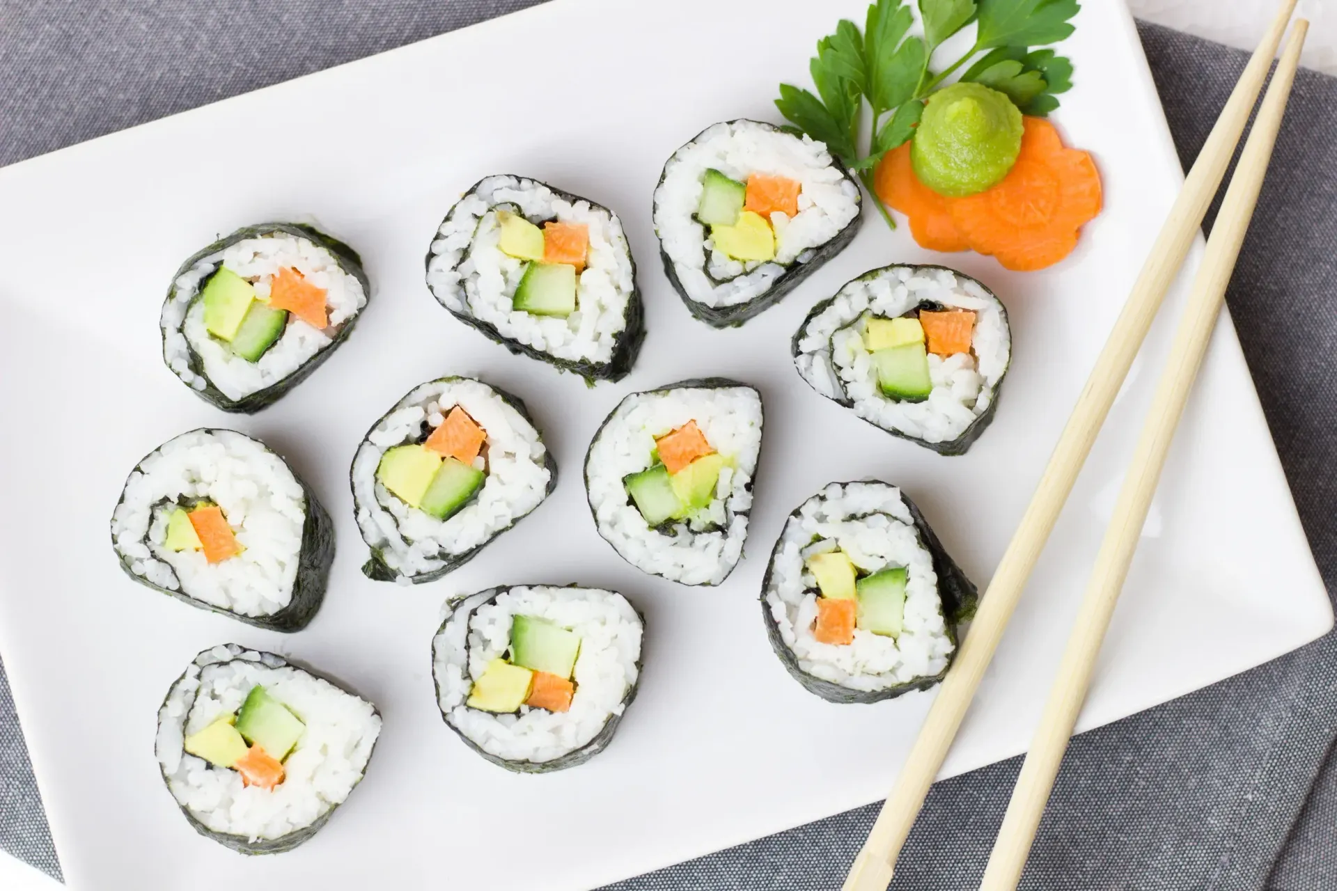 A white plate topped with sushi rolls and chopsticks