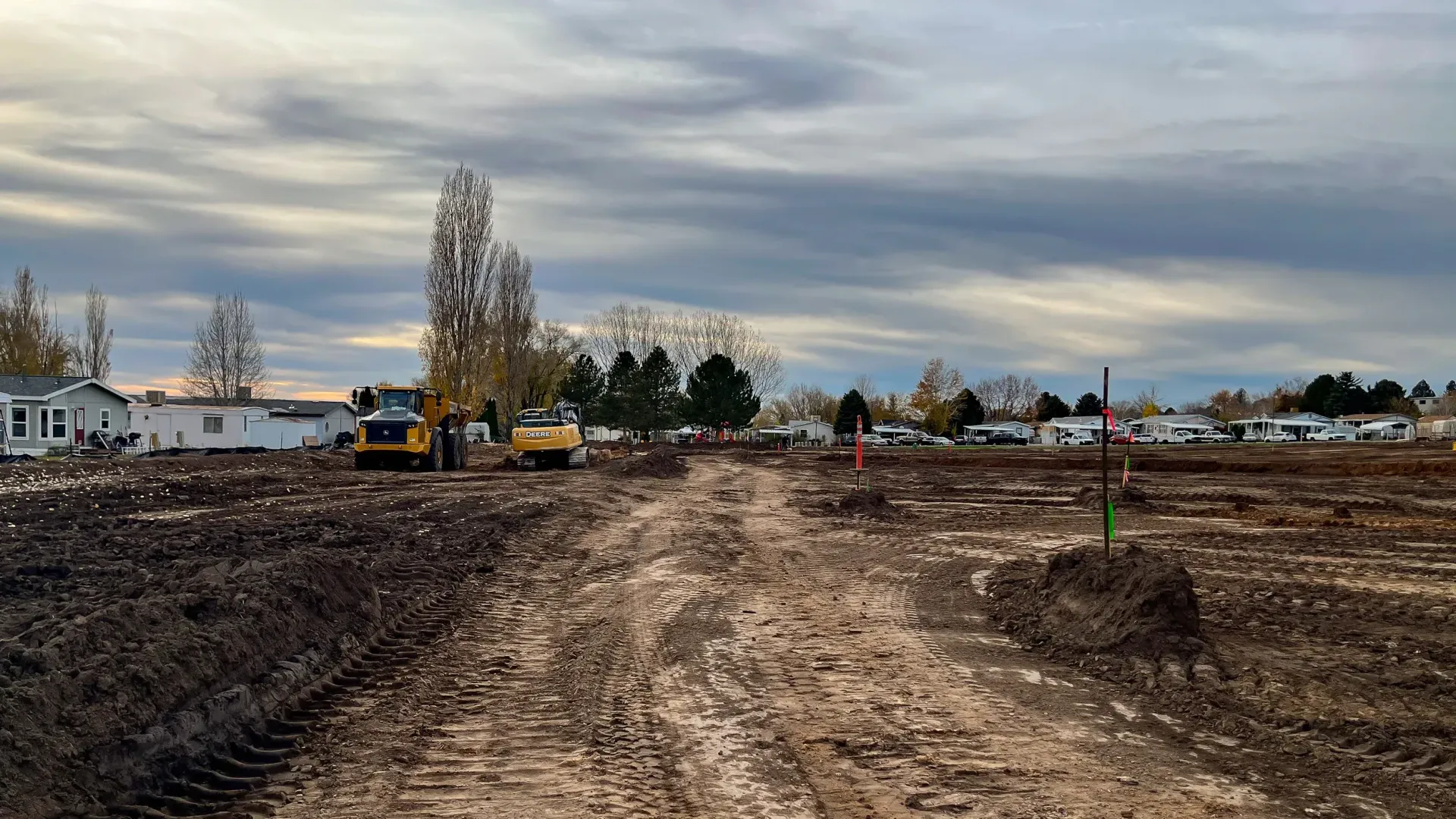 A bulldozer is driving down a dirt road in a field.