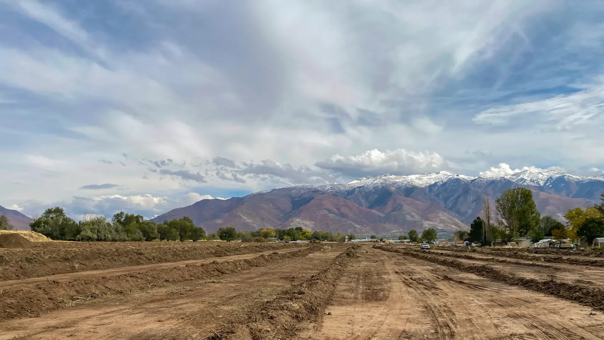 A dirt road going through a field with mountains in the background.